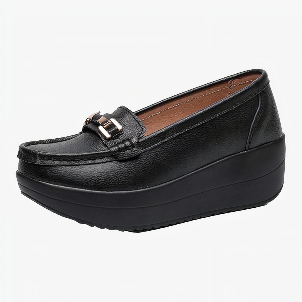 Mocassin noir à semelle épaisse de profil avec une boucle dorée sur le devant