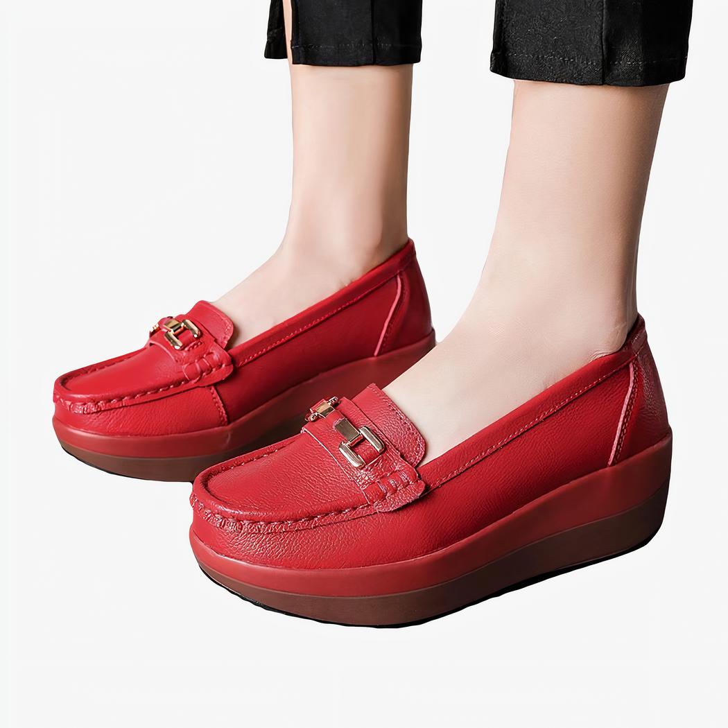 Une femme debout avec des mocassins rouges et une petite boucle en or pour finition