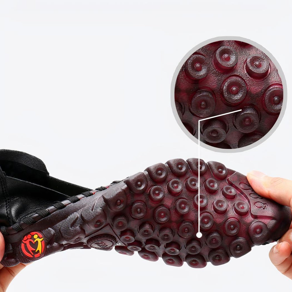 Jambes croisées avec des chaussures rouges au pieds à côtés d'autres chaussures marrons, noires, et blanches.