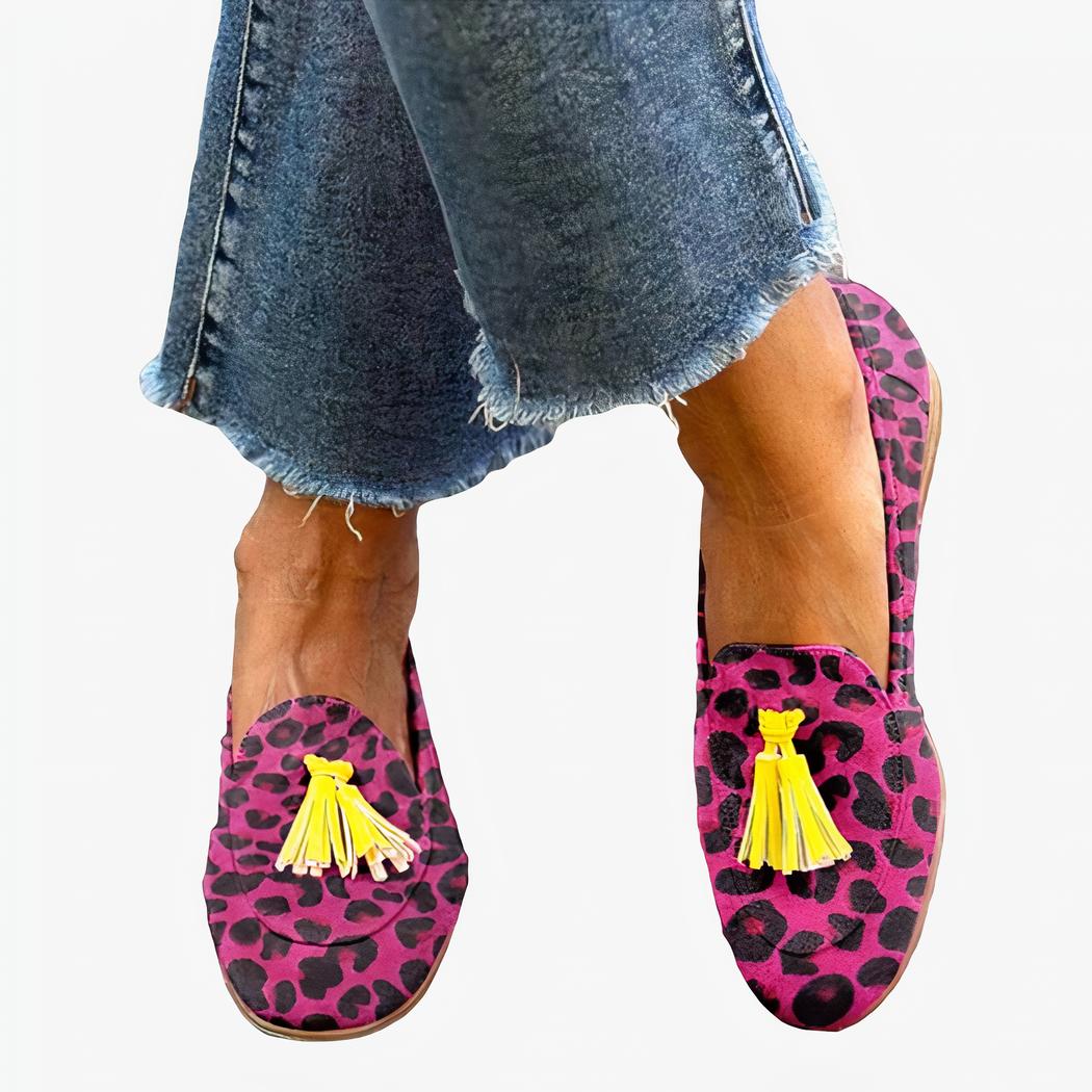 Femme debout les jambes croisées dans la rue portant un jean et des mocassins à glands imprimé léopard rose