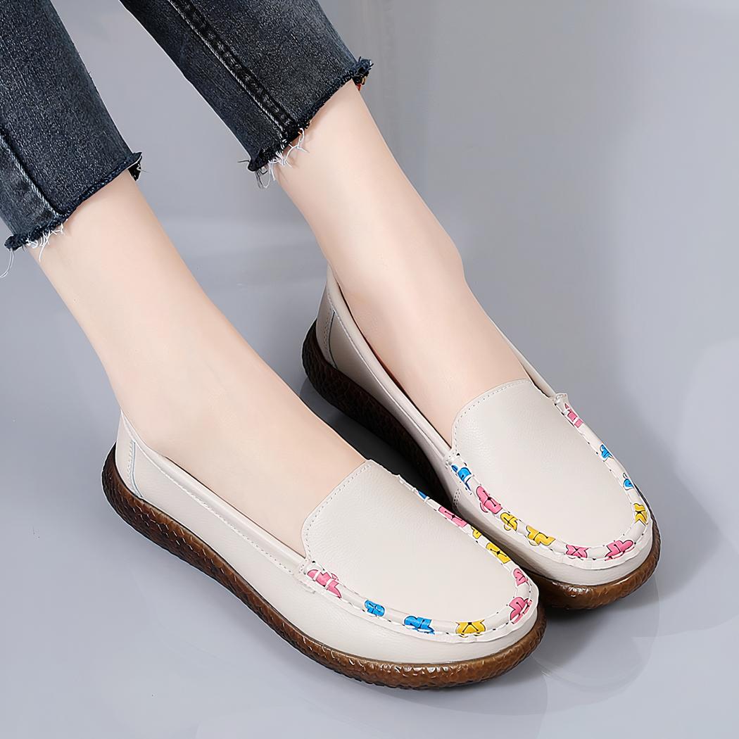 Photo d'une paire de mocassins beige portée par une femme au pantalon noir, sur fond gris