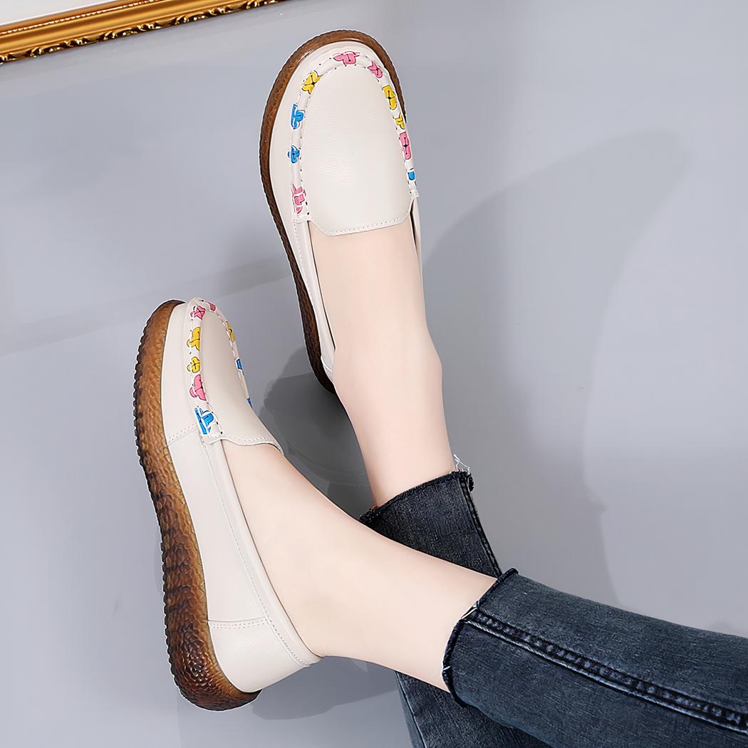 Photo d'une paire de mocassins blancs portée par une femme avec un jean noir, sur fond gris