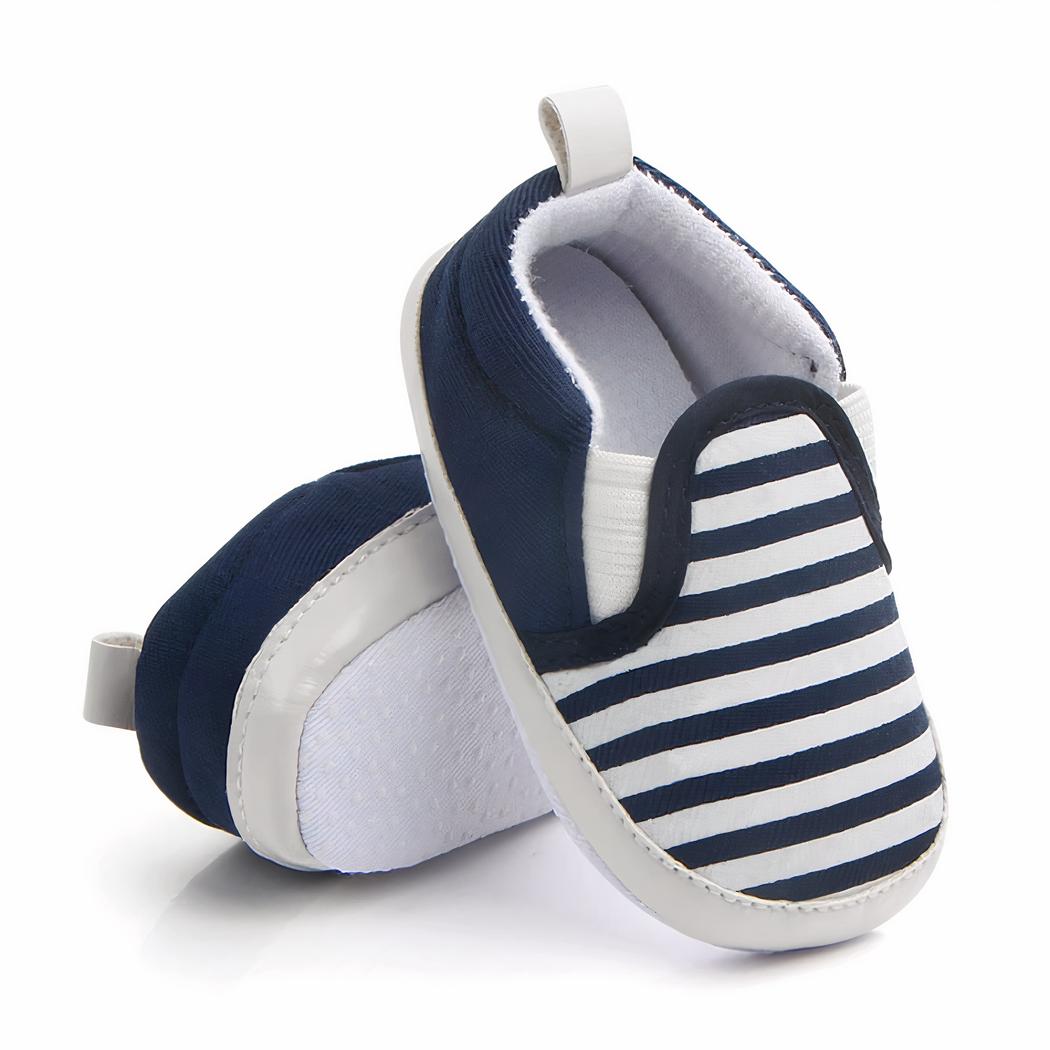 Sur fond blanc, 3 mocassins pour bébé rayés noir, beige et vert avec semelle blanche et élastiqués sur les côtés