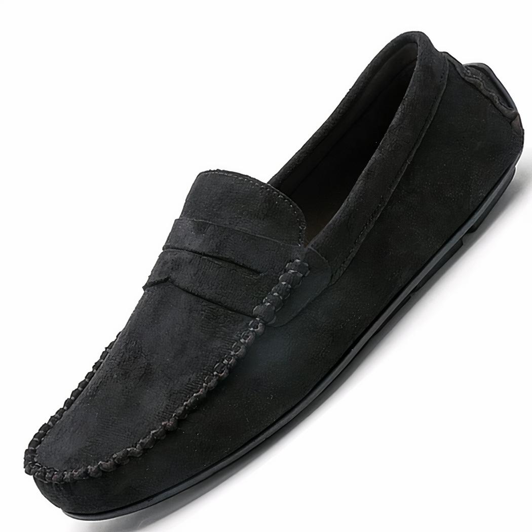 Pieds croisés munis de mocassins noirs sur un carrelage gris foncé