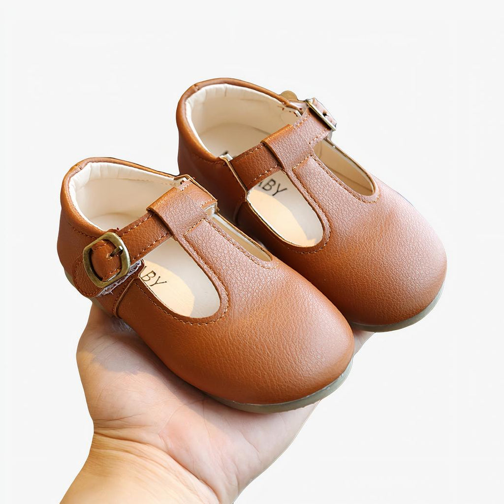 petit mocassin pour fille en faux cuir marron porter par une main d'adulte