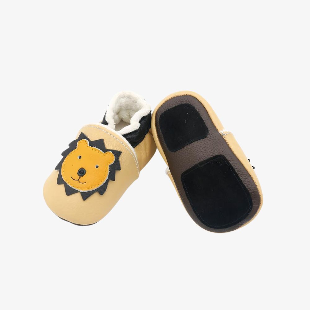 Mocassins souples pour bébé en cuir marron foncé avec tête de girafe jaune. On voit de la peluche douce beige à l'intérieur.