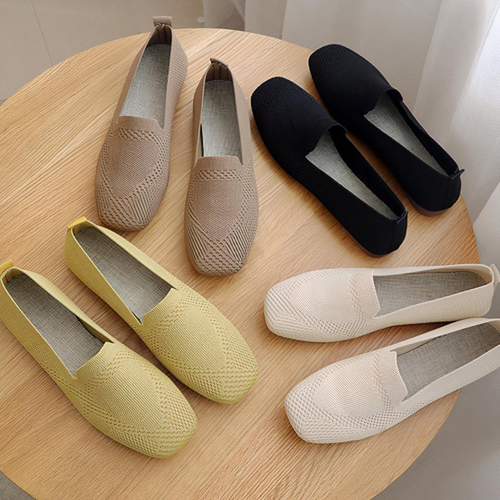 Sur une table en bois , 3 mocassins bout carré en maille jaune, noir et beige . On voit une main qui plie un mocassin pour montrer sa souplesse
