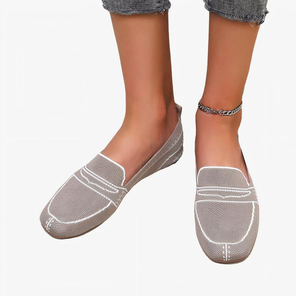 Paire de mocassins gris en maille avec coutures blanches dessinées portée pieds nus avec un jean et une chaine à la cheville
