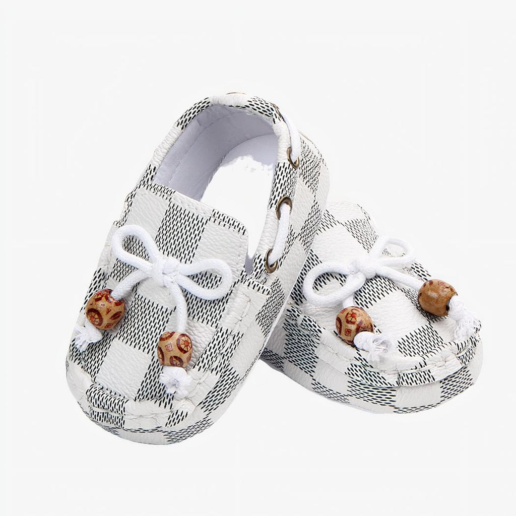 Paire de mocassins à carreaux blancs, avec un lacet et deux perles décoratives