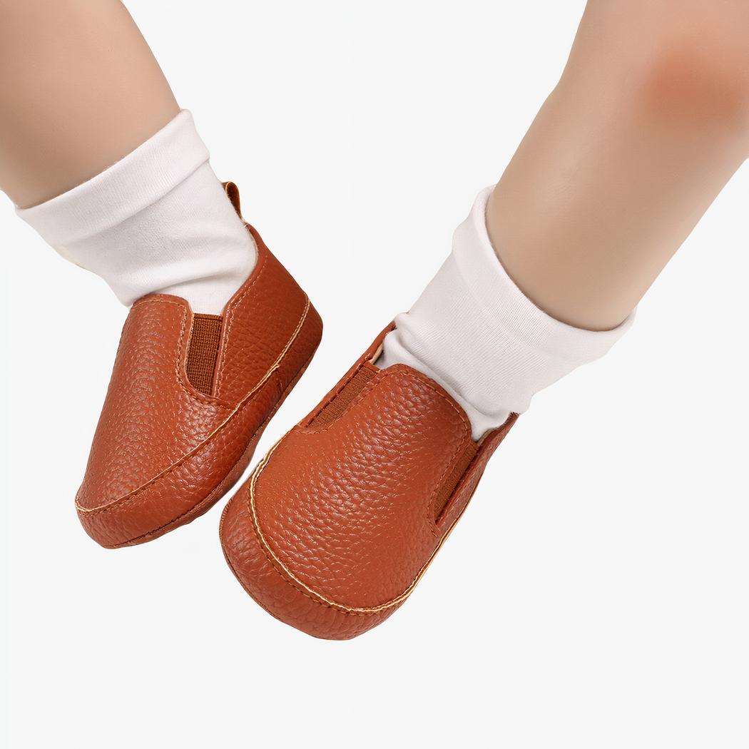 Bébé portant des chaussettes blanches et des mocassins unis marrons en cuir synthétiques