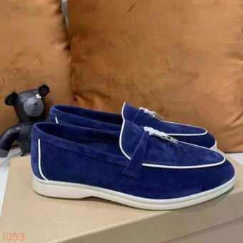 Mocassin en daim bleu avec liserais blanc et un gland dur le devant de la chaussure qui est poser sur une boite à chaussure