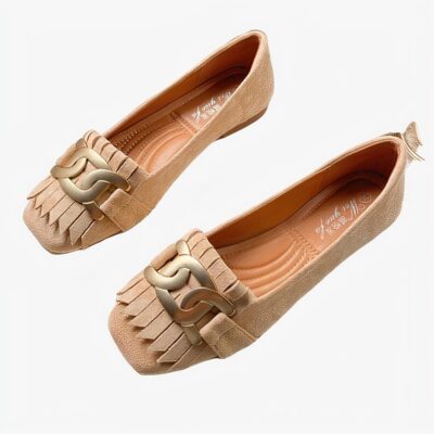 mocassin en daim beige avec un gland et un anneau sur le dessus poser sur une table