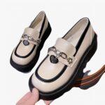 Photo d'une paire de mocassins à plateforme blanche posée sur un tabouret gris