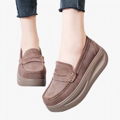 Femme portant des mocassins marrons avec plateforme. On voit seulement ses chevilles.
