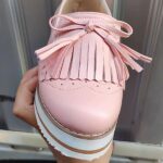 Photo d'un mocassin rose compensé à franges porté devant une porte