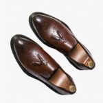 Mocassins classiques pour homme en cuir marron brillant, ornés de glands raffinés sur le dessus. Leur design élégant et intemporel convient parfaitement aux occasions formelles ou décontractées, offrant un mélange harmonieux de sophistication et de confort. Une finition soignée pour un look chic et indémodable.