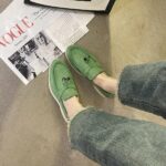 mocassin vert en daim porter par une femme avec un livre devant ses pied