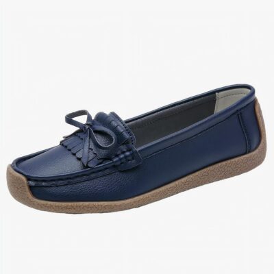 mocassin en cuir bleu foncé avec un gland sur le dessus poser sur un fond blanc