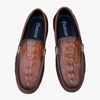 Mocassins crocodiles marron sur fond gris.