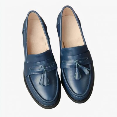 mocassin bleu en cuir à talon avec un gland sur le dessus, poser sur un sol gris