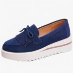 mocassin en daim bleu à gland compensé à semelle blanche sous sur un fond blanc