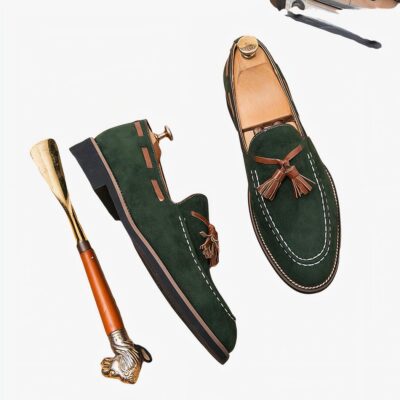 Paire de mocassins verts à pompons avec un chausse-pied à côté