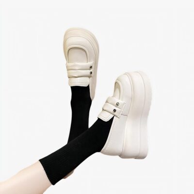 Mocassins blancs épais portés par une personne dont on voit seulement les mollets.