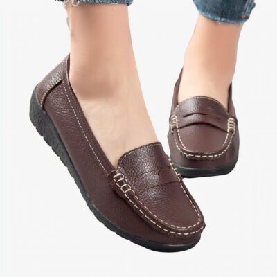 Mocassins marrons portés par une femme dont on voit seulement les chevilles.