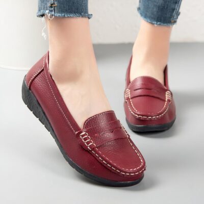 Photo d'une paire de mocassins rouges portée par une femme sur un sol gris