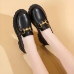 Photo d'une paire de mocassins à plateforme noire portée par une femme sur fond beige