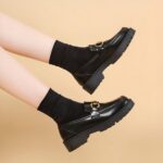 Photo d'une paire de mocassins à plateforme noire portée par une femme sur fond beige