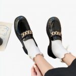 Mocassins noirs en cuir à talon portés par une femme avec des chaussettes blanches