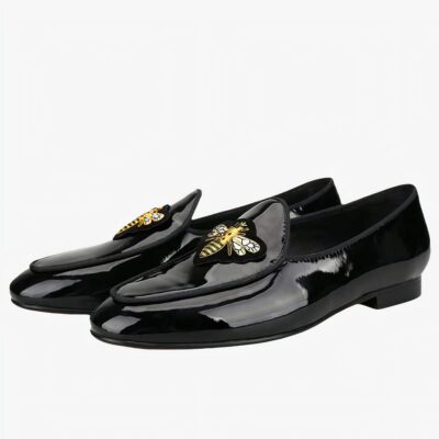 Mocassins brillant avec papillon en or comme boucle sur fond blanc