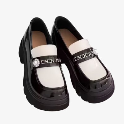Mocassins vernis bicolores à semelle épaisse blancs et noirs avec une chainette en métal sur le devant.