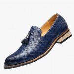 Un mocassin en cuir bleu tressé avec semelle clair et glands décoratifs sur un fond blanc.