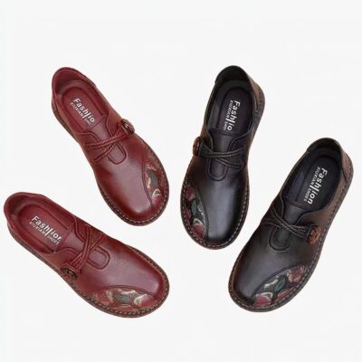 Deux paires de chaussures posées sur le sol. Une rouge et une noire avec des motifs de fleurs sur le devant.