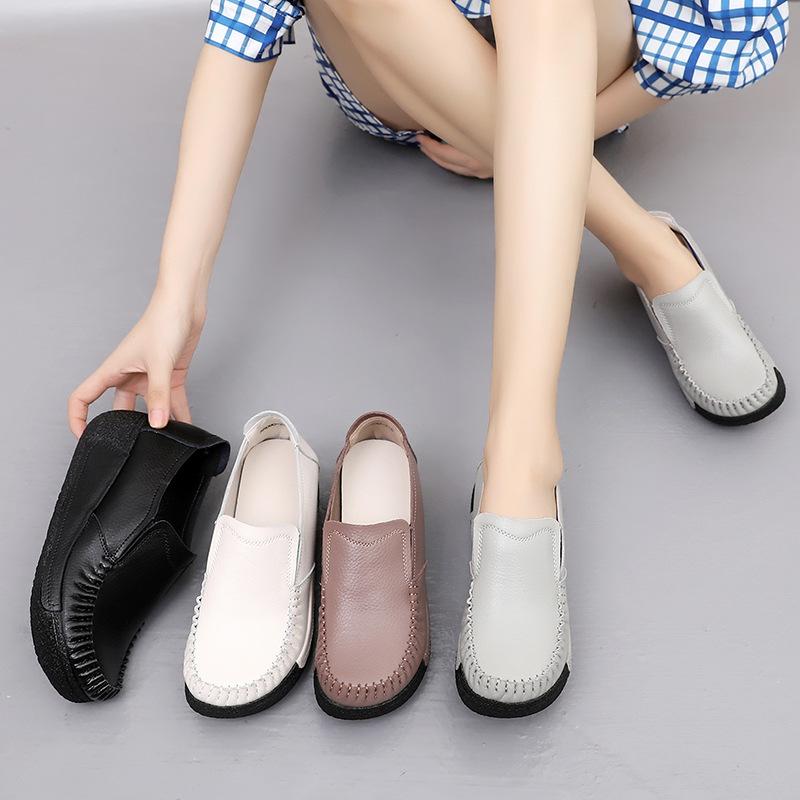 Jambe d'une femme avec des chaussures grises aux pieds avec d'autres chaussures à côté d'elle, noire, blanche et marron