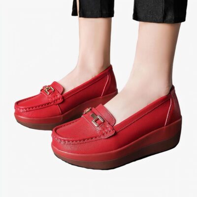 Une femme debout avec des mocassins rouges et une petite boucle en or pour finition