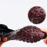Jambes croisées avec des chaussures rouges au pieds à côtés d'autres chaussures marrons, noires, et blanches.