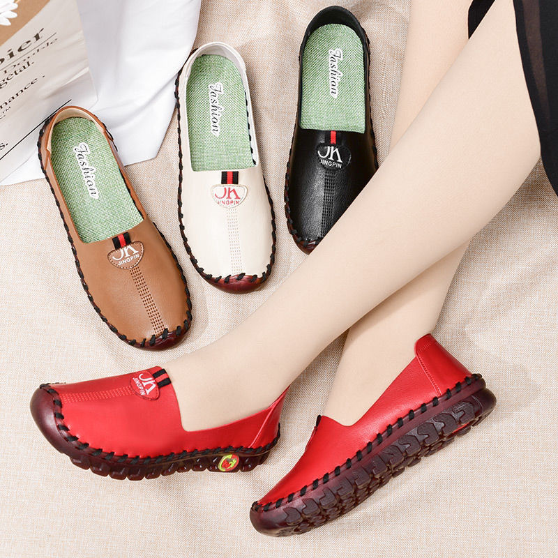 Jambes croisées avec des chaussures rouges au pieds à côtés d'autres chaussures marrons, noires, et blanches.