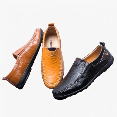 3 mocassins de couleur noire, camel et marron disposés sur un sol noir