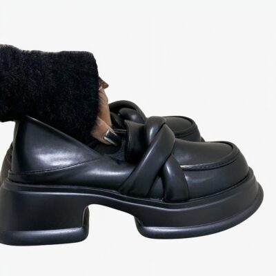 Mocassins en cuir synthétique à plateforme noire pour femmes avec un fond beige et une femme qui tiens la paire de chaussure