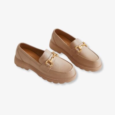 Paire de mocassins beige pour femme avec une boucle dorée sur le dessus, sur fond gris clair.