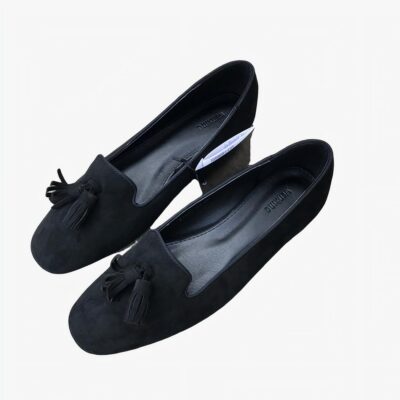 Paire de mocassins noirs effet daim posés sur un sol gris en béton