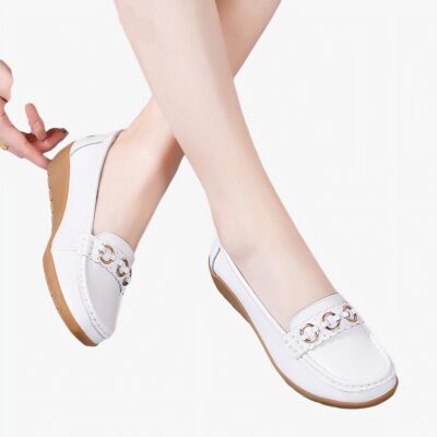 Jambes d'une femme assise portant les mocassins compensés blancs