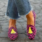 Femme debout les jambes croisées dans la rue portant un jean et des mocassins à glands imprimé léopard rose