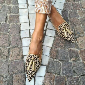 Femme dans la rue les pieds croisés portant les mocassins à bout pointu léopard doré