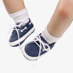 Jambes de bébé portant des chaussettes blanches et des mocassins bleus style bateau