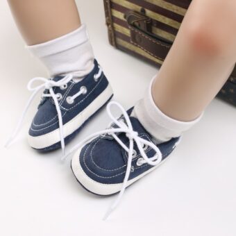Jambes de bébé portant des chaussettes blanches et des mocassins bleus style bateau