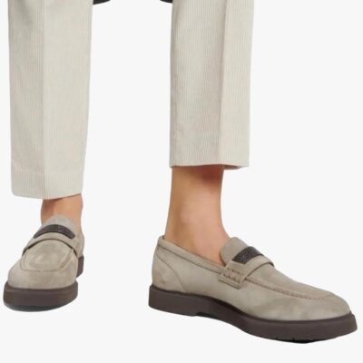 on voit les pieds d'une femme qui porte un pantalon de tailleur beige et des mocassins gris en daim véritable pour femme